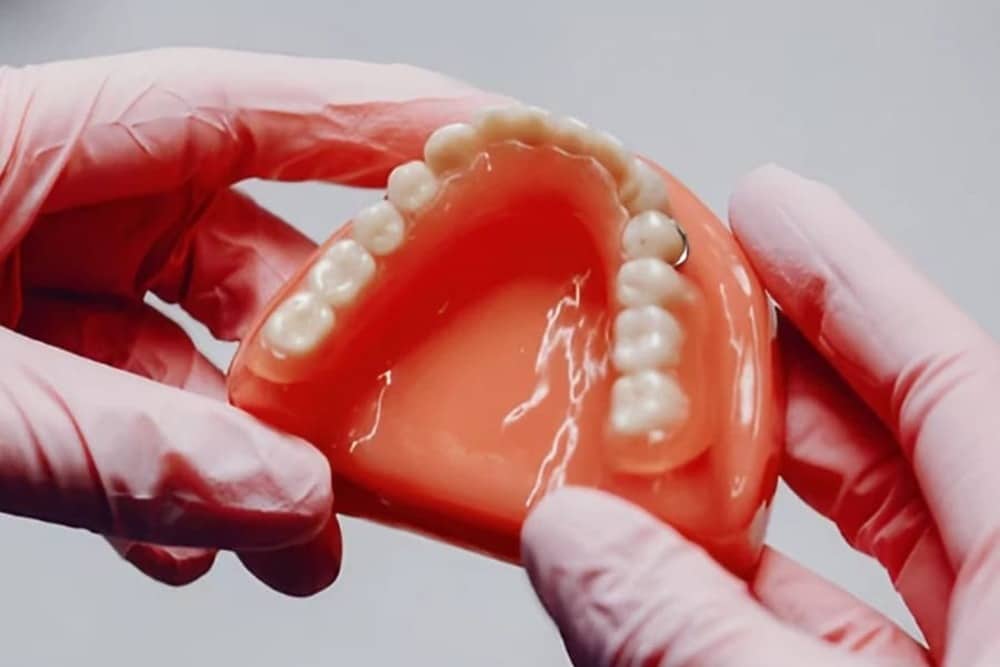 dentista mostrando maqueta de prótesis dentales