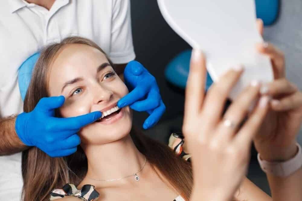 dentista mostrando al espejo sonrisa alineada paciente