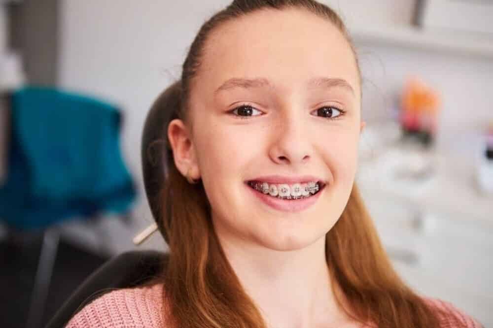 adolescente sonriente mostrando ortodoncia