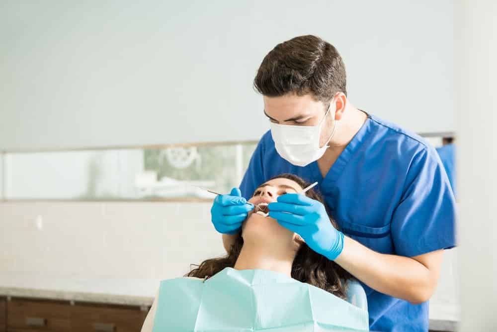 dentista masculino examinando mujer-joven-tallador dental clinica medica