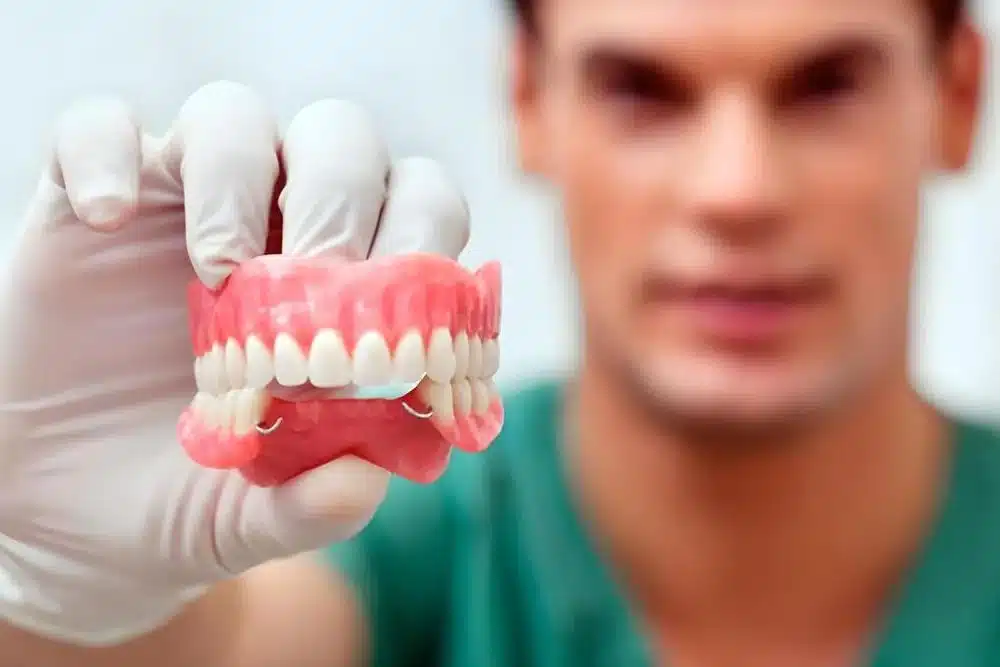 dentista sujetando modelo prótesis dental
